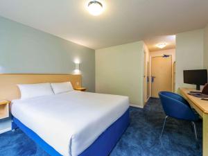 邓迪ibis budget Dundee Camperdown的酒店客房设有一张大床和一张书桌。