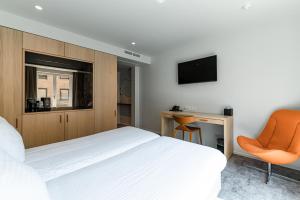 布鲁日Hotel Le Bois De Bruges的卧室配有白色的床和橙色椅子