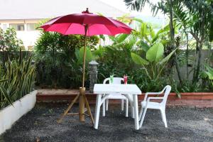 拉迈BT豪宅酒店的一张桌子和两把椅子以及一把红色雨伞