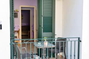 科尔萨诺La Torretta Dei Sogni的阳台配有桌椅和绿门