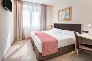 塞维利亚加泰罗尼亚希斯帕利斯酒店的酒店客房设有一张大床和一张书桌。