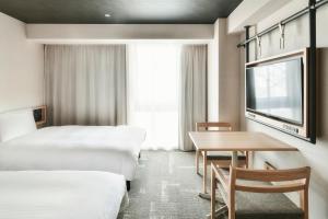 松山REF Matsuyama City Station by VESSEL HOTELS的酒店客房设有两张床和一张桌子。