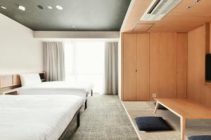 松山REF Matsuyama City Station by VESSEL HOTELS的酒店客房设有两张床和一张桌子。