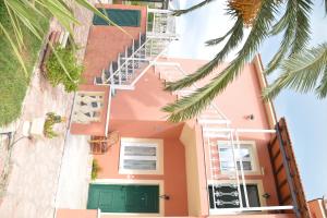 斯达林Marilena Apartments的粉红色的房子,有绿门和棕榈树