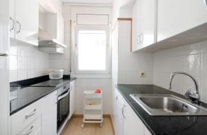 卡莱利亚德帕拉弗鲁赫尔Precioso apartamento en primera línea de mar en Calella de Palafrugell的厨房配有白色橱柜、水槽和窗户。