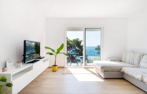 卡莱利亚德帕拉弗鲁赫尔Precioso apartamento en primera línea de mar en Calella de Palafrugell的带沙发和电视的白色客厅