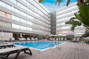 巴塞罗那奥林匹克套房酒店及Spa别墅的酒店游泳池设有椅子,酒店大楼