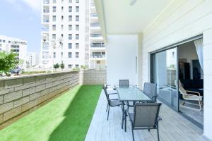 纳哈里亚Luxury Living at Achziv Beach Apartment by Sea N' Rent的阳台配有桌椅和草地。