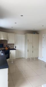 康多纳Modern Home Carndonagh的厨房配有白色橱柜和白色瓷砖地板。