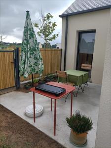 HillionProche GR34 , Studio "Estrella" , petit cocon accueillant的一个带桌子和遮阳伞的庭院