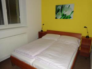 利普托斯基米库拉斯德玛诺瓦238酒店的一张带白色床单的床铺,位于一个黄色墙壁的房间