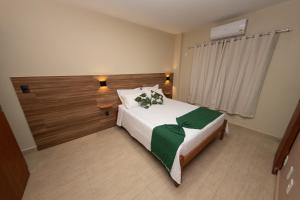 圣若昂-德雷Terra D` Ouro Apart Hotel的卧室配有一张带绿毯的大型白色床