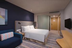 无锡无锡太湖新城智选假日酒店的酒店客房,配有一张床和一张蓝色椅子