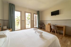 卡斯特沃托诺Plana Resort & SPA的卧室配有一张白色的床、书桌和电视。