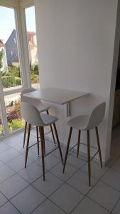 Adorf4* Ferienwohnung Neukirchen im Erzgebirge的窗户客房内的一张白色桌子和两把椅子