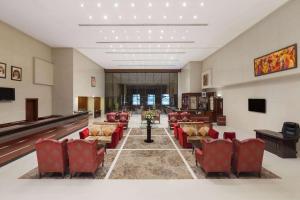 阿吉曼Ramada Hotel & Suites by Wyndham Ajman的一间设有红色椅子和钢琴的等候室