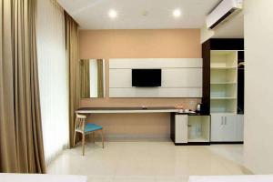 日惹Sans Hotel Nagari Malioboro的客厅配有书桌和电视。