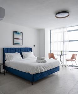 特拉维夫De' Mar Florentine Hotel By Peraia的一间卧室配有蓝色的床、两把椅子和一张桌子