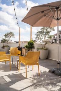 特拉维夫De' Mar Florentine Hotel By Peraia的庭院设有黄色椅子和遮阳伞。