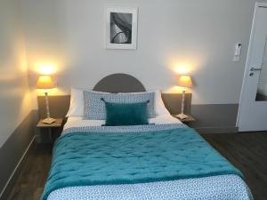 图尔地址酒店的一间卧室配有一张带蓝色床单的大床和两盏灯。