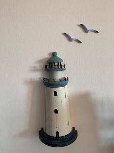 丽都玛里尼Casa Bianca & BLU a due passi dal mare的一座灯塔的模型,两只鸟飞翔