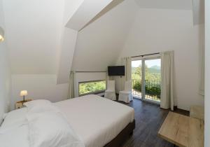 佩斯卡塞罗利Relais Chalons d’Orange的白色的卧室设有床和大窗户