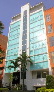 麦德林Hotel Suite Comfort的一座高大的建筑,前面有一棵棕榈树