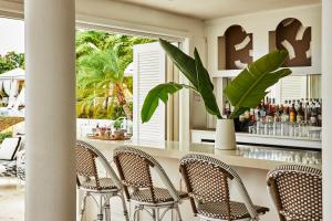 Meads BayMalliouhana Resort Anguilla的一间带椅子的餐厅和一间种植了植物的酒吧