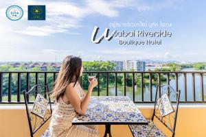 尖竹汶USABAI Riverside Boutique Hotel的坐在阳台上桌子上的女人