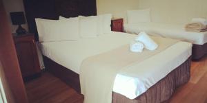 麦凯乡村广场汽车旅馆的配有白色床单的酒店客房内的两张床