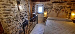 Frassinorob&b La Corte dei Cerri- Il Piccolo Chalet的一间卧室设有一张床和石墙