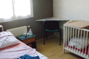 瓦朗斯Chambre chez l'habitant的一间卧室配有一张婴儿床、一张桌子和一张书桌。
