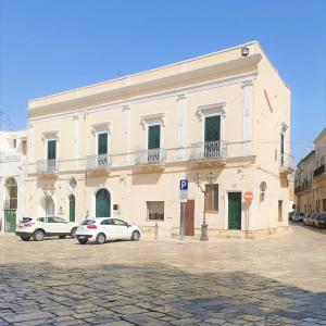 梅萨涅Antico Palazzo Murri的一座白色的大建筑,前面有汽车停放