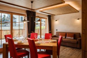 利维尼奥Chalet Bellavista的一间带木桌和红色椅子的用餐室