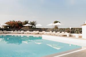 拉格朗德默特Hôtel Les Corallines – Thalasso & Spa的一个带白色椅子和遮阳伞的游泳池