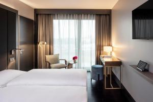 柏林AMANO East Side的配有一张床、一张书桌和一扇窗户的酒店客房