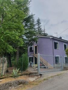 TossiciaFlamignano: un paradiso nel verde的一座紫色的房子,前面有栅栏