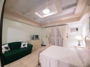 马尼拉Casa Micarosa Hotel的卧室配有白色的床和绿色沙发