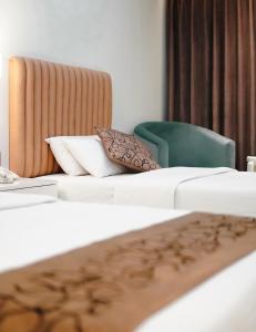 库克斯巴扎白兰花酒店的酒店客房,设有两张床和一把绿色椅子