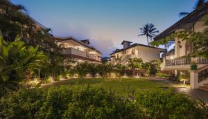 坎撒林Heritage Village Resort & Spa Goa的拥有草坪和建筑的度假村庭院