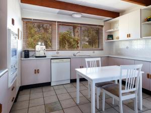 霍克斯内斯特Bennett's Beach Cottage的白色的厨房配有白色的桌子和椅子