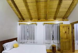 TepelenëBujtina Peshtan Guesthouse&Camping的一间卧室设有两张床和木制天花板