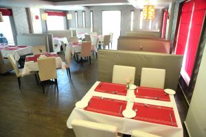 柴瑞海滩Paravoor Galaxy Hotel的餐厅设有白色的桌子和白色的椅子以及红色的桌子。
