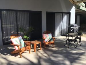 埃利奥特港Port Elliot rural retreat的庭院配有两把椅子、一张桌子和一张桌子以及椅子。