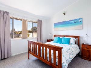 霍克斯内斯特Surfs Up的一间卧室配有一张带蓝色枕头的床和一扇窗户。