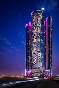 迪拜Paramount Hotel Dubai的一座高大的建筑,晚上有紫色的灯光
