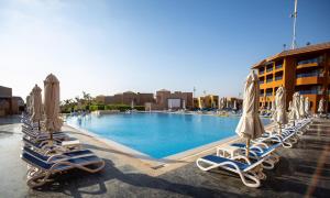艾因苏赫纳Cancun Sokhna Resort & Villas的游泳池里的一排躺椅和遮阳伞