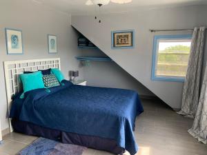 HermitageTurtles Nest Bahamas的一间卧室设有蓝色的床和楼梯。