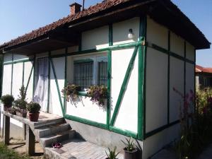维索科Kuća na selu-Mutvak-的一间设有绿色和白色窗户的小房子
