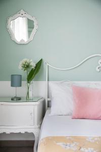 阿奇卡斯泰洛奥坦西亚别墅住宿加早餐旅馆的一张带粉红色枕头和镜子的白色床